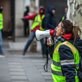 Airport workers in high-visibility vests during strike action with megaphone