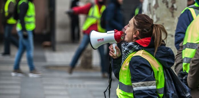 Airport workers in high-visibility vests during strike action with megaphone