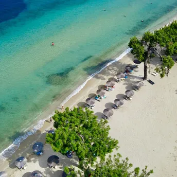 Aerial view of sandy beach with umbrellas and clear turquoise water in Thassos