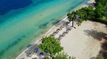 Aerial view of sandy beach with umbrellas and clear turquoise water in Thassos