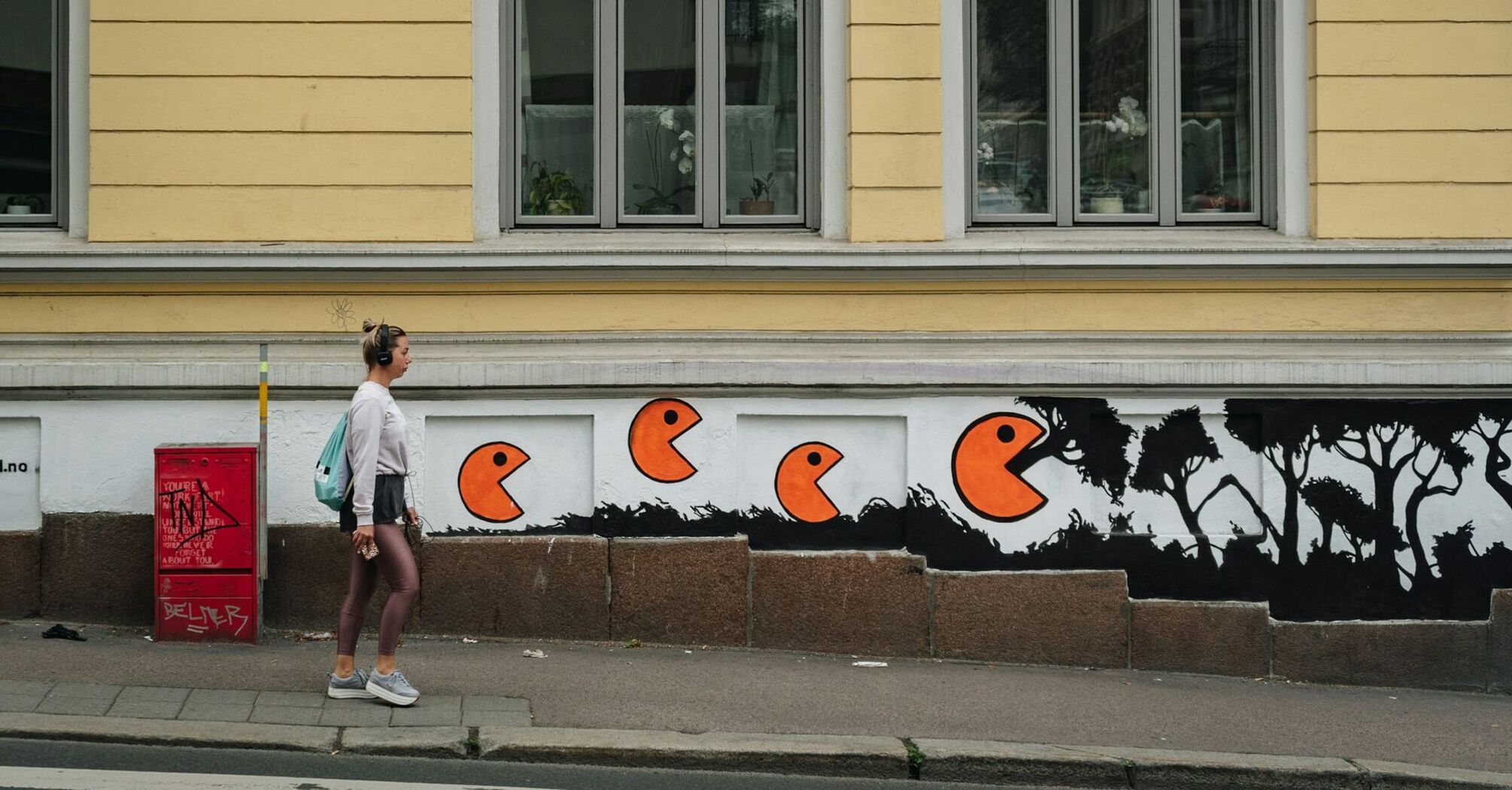 Street mural with orange figures on building wall