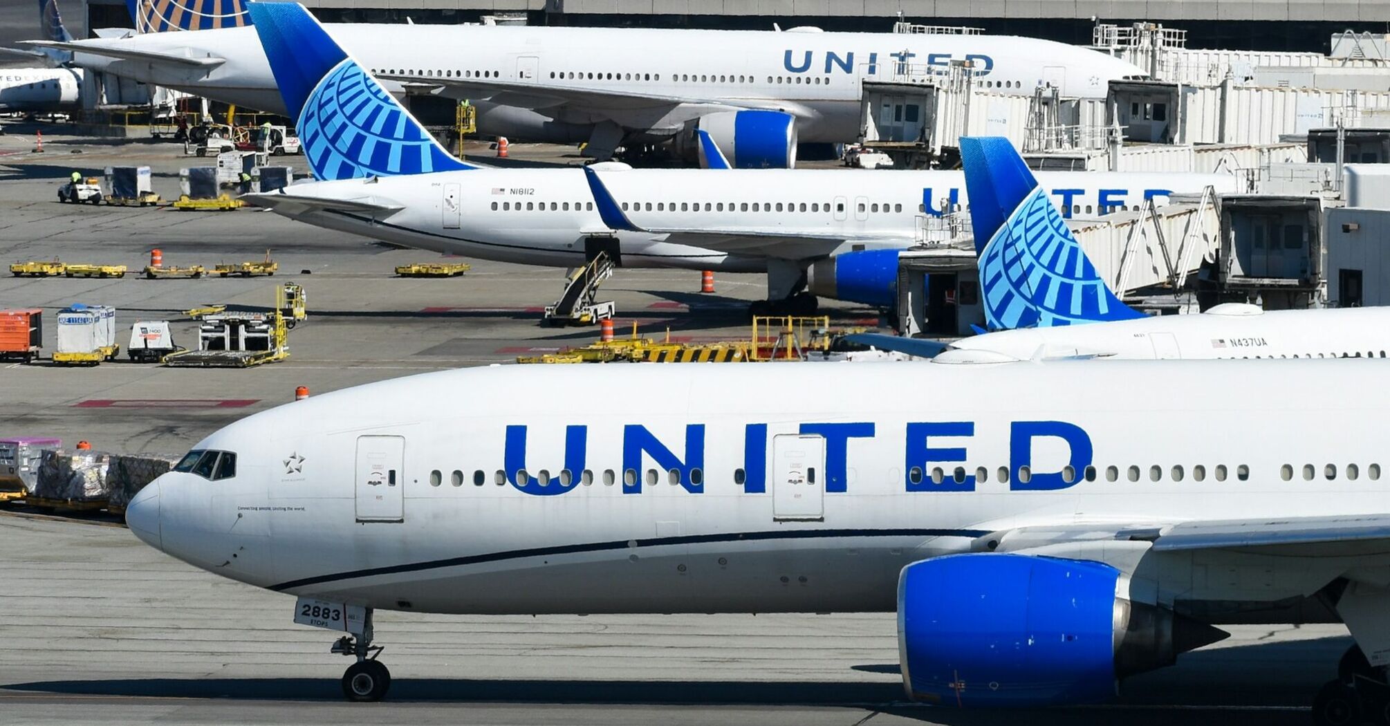 United Airlines aircraft parked at airport gate with ground equipment