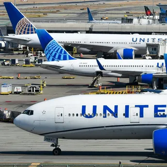 United Airlines aircraft parked at airport gate with ground equipment