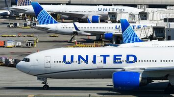 United Airlines aircraft parked at airport gate with ground equipment