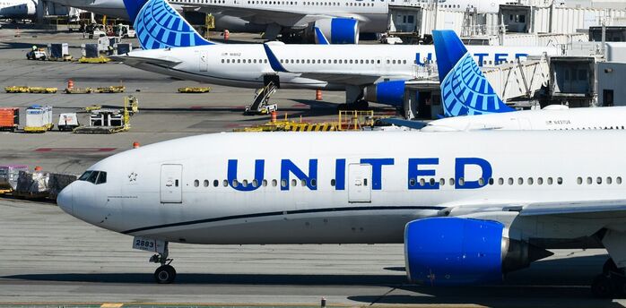 United Airlines aircraft parked at airport gate with ground equipment