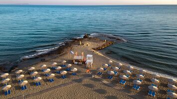 Sandy beach with sun loungers, umbrellas and lifeguard tower on a narrow peninsula