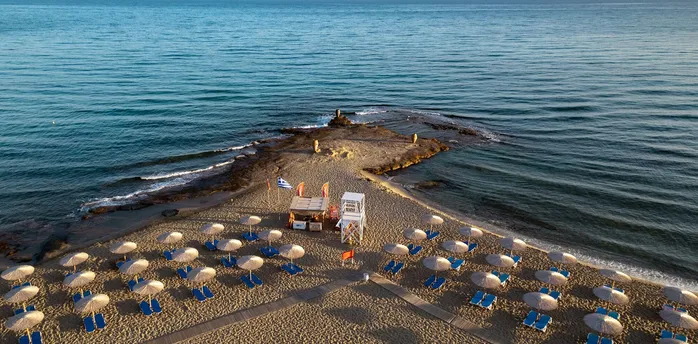 Sandy beach with sun loungers, umbrellas and lifeguard tower on a narrow peninsula