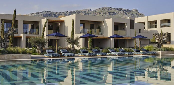 Resort buildings with pool and sun loungers in front