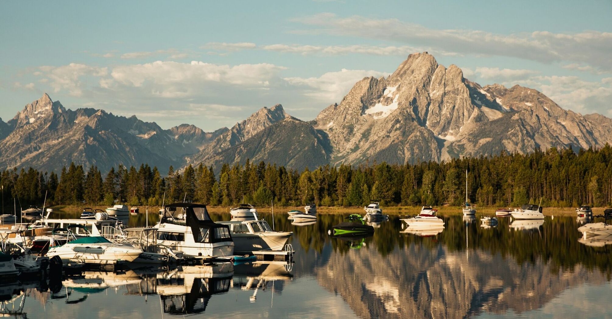 Calm marina with small boats and mountains in the background