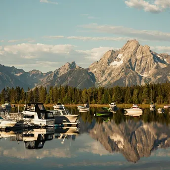 Calm marina with small boats and mountains in the background