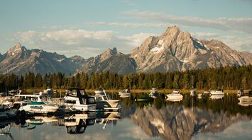 Calm marina with small boats and mountains in the background