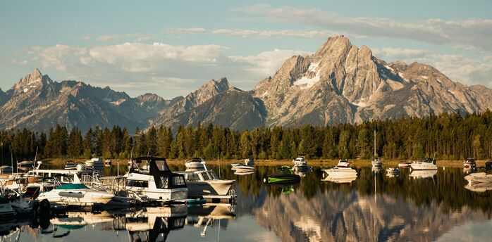 Calm marina with small boats and mountains in the background