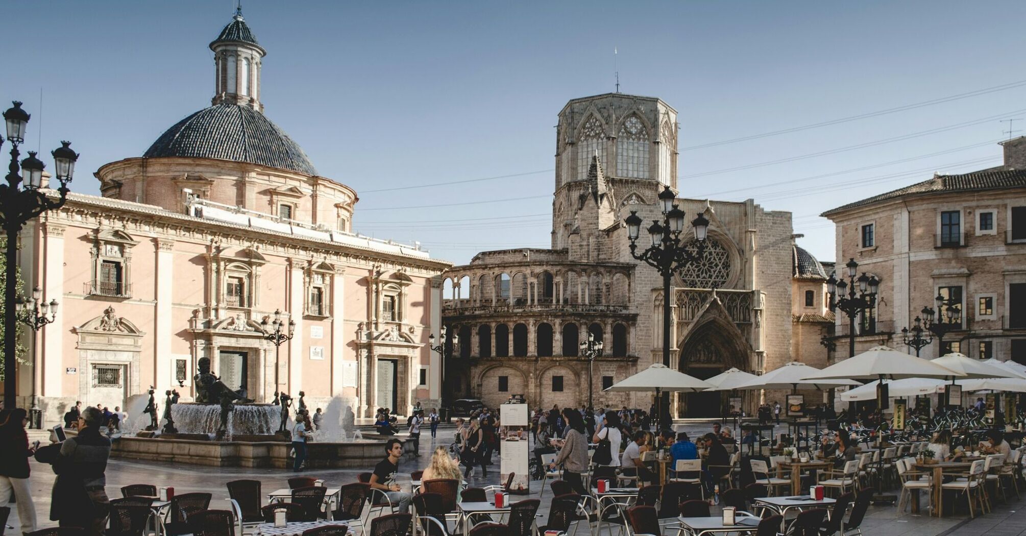 Busy city square with outdoor café seating and historic buildings