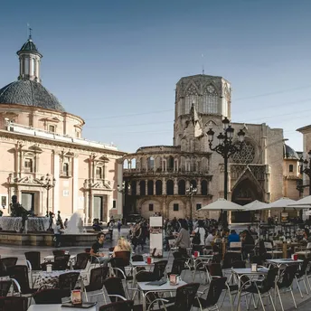 Busy city square with outdoor café seating and historic buildings