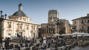 Busy city square with outdoor café seating and historic buildings