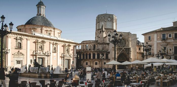 Busy city square with outdoor café seating and historic buildings