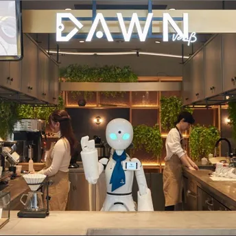 Robot assistant working behind a café counter with staff preparing drinks