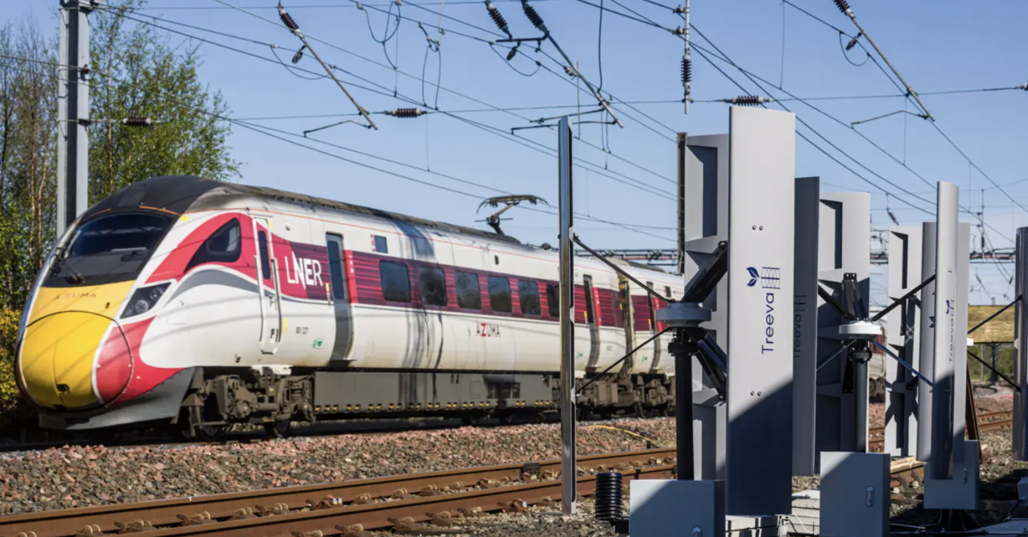 LNER train passing trackside turbines beside railway