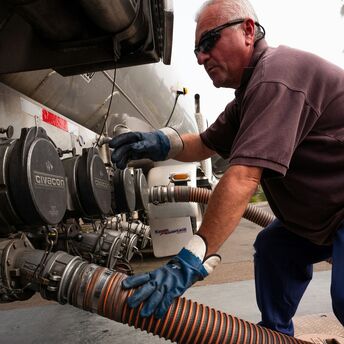 Technician connecting hose to fuel tanker
