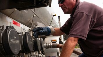 Technician connecting hose to fuel tanker