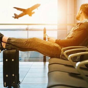 Passenger waiting at airport gate watching plane take off