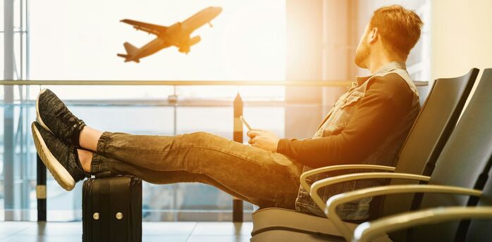 Passenger waiting at airport gate watching plane take off