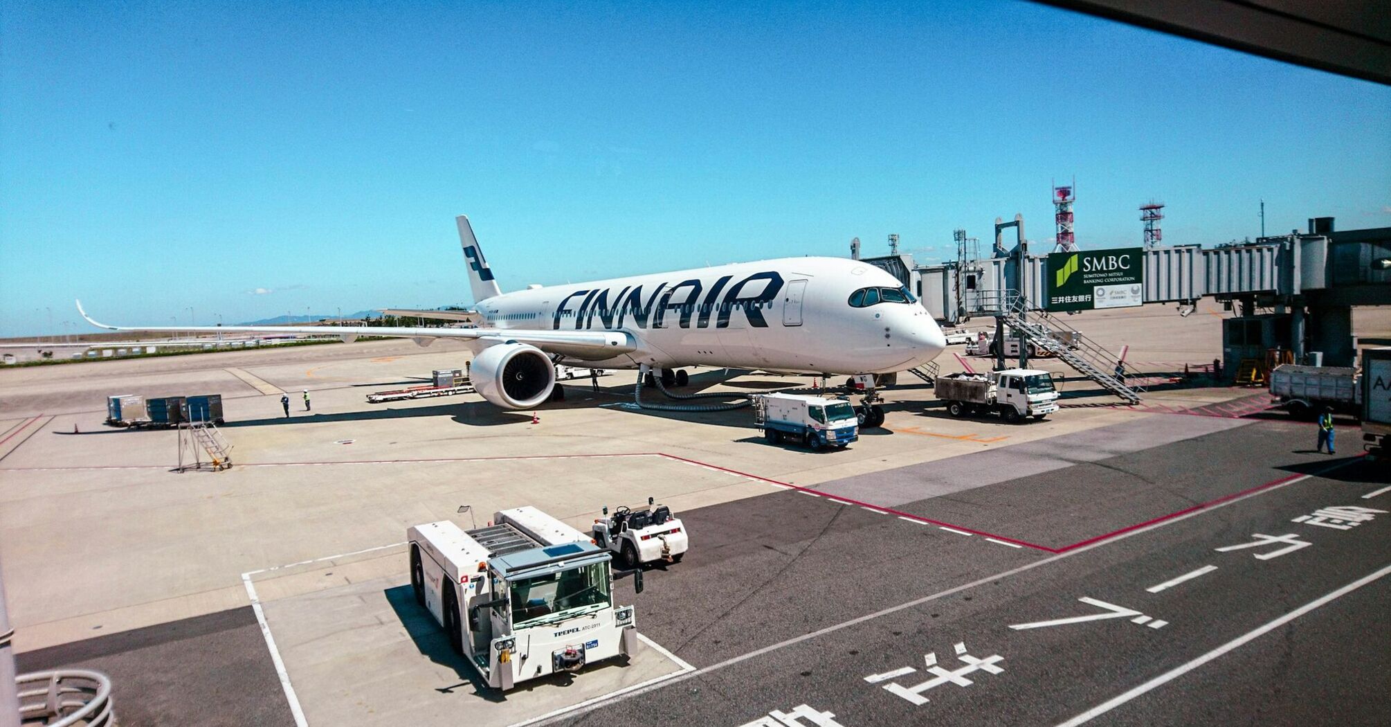 Finnair aircraft parked at airport gate with ground vehicles nearby