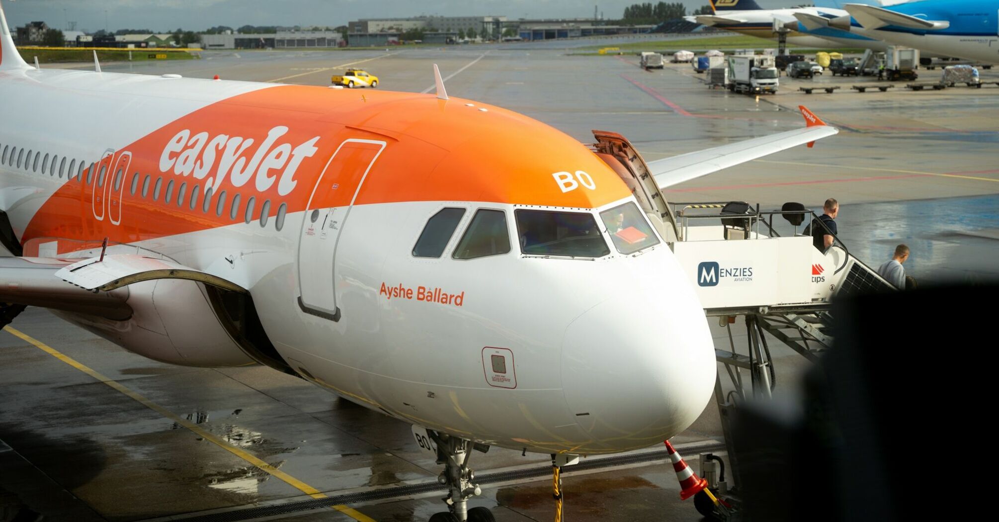 easyJet aircraft parked at airport stand with ground crew and boarding stairs