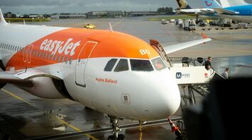 easyJet aircraft parked at airport stand with ground crew and boarding stairs