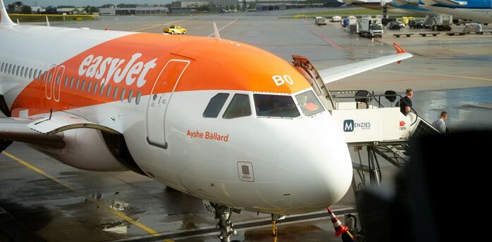 easyJet aircraft parked at airport stand with ground crew and boarding stairs