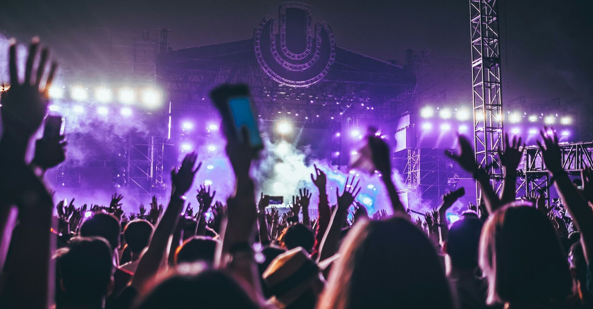 Festival crowd facing a purple-lit stage