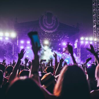 Festival crowd facing a purple-lit stage