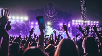 Festival crowd facing a purple-lit stage