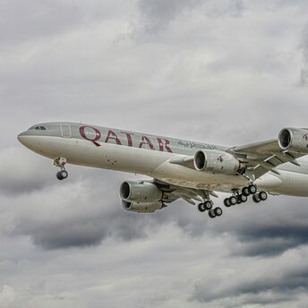 Qatar Airways aircraft flying through cloudy skies