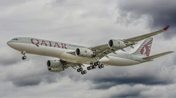 Qatar Airways aircraft flying through cloudy skies