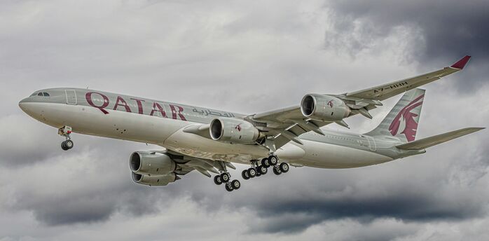 Qatar Airways aircraft flying through cloudy skies