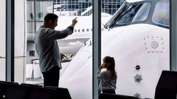 Family watching an aircraft from an airport terminal