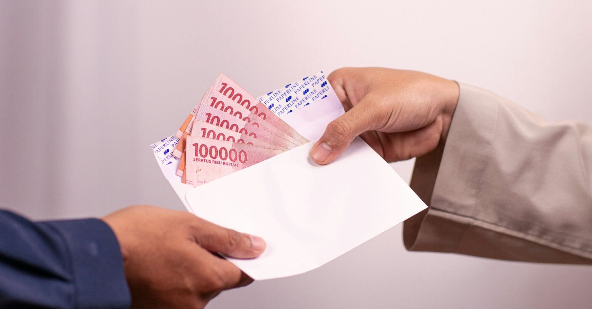 Hand giving envelope with cash