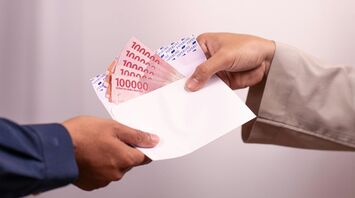 Hand giving envelope with cash