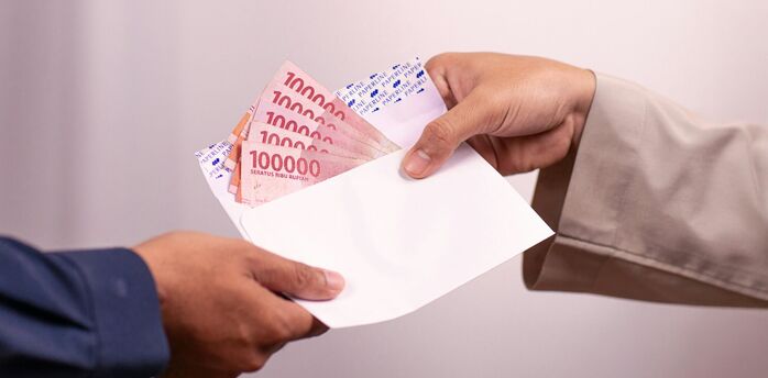 Hand giving envelope with cash