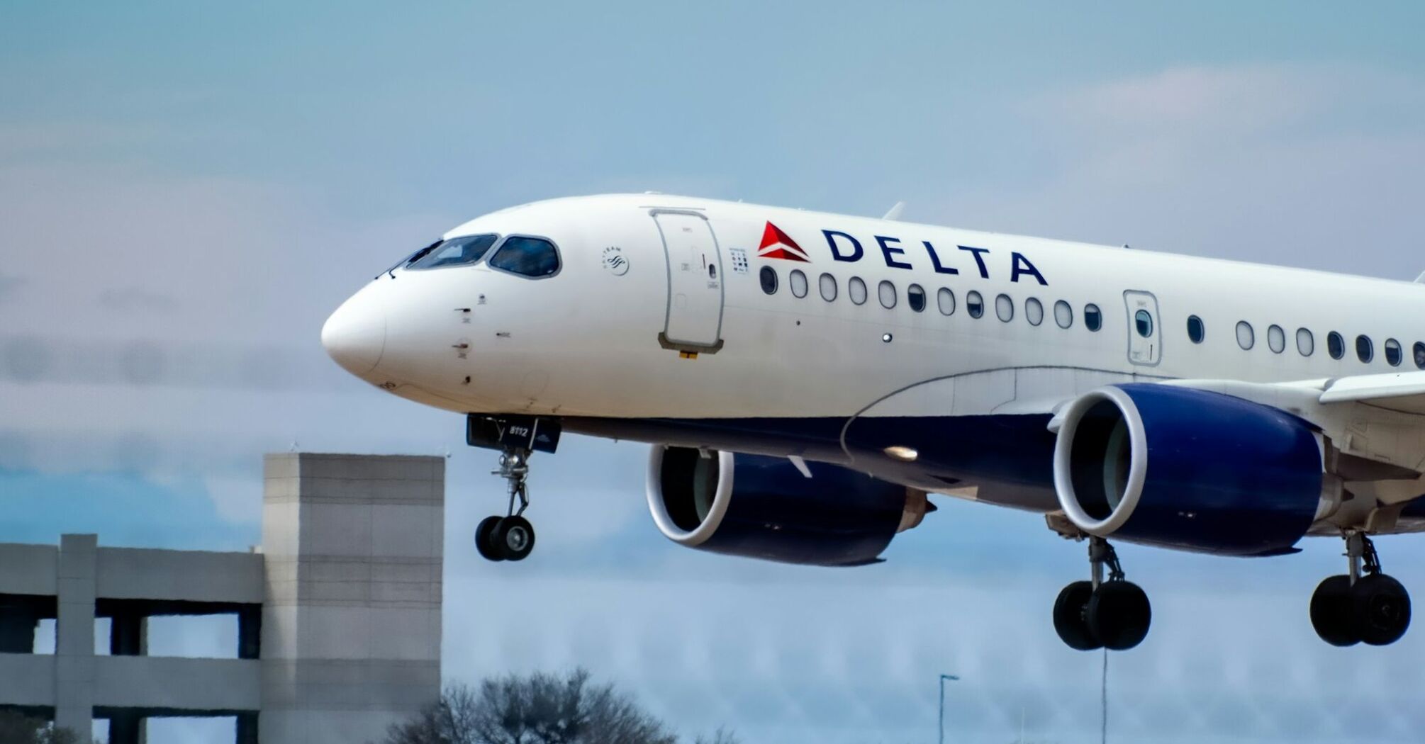 Delta Air Lines aircraft landing against a cloudy blue sky