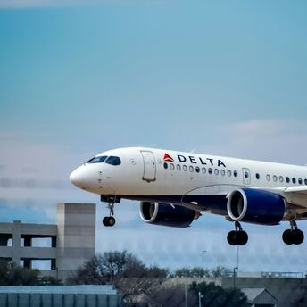 Delta Air Lines aircraft landing against a cloudy blue sky