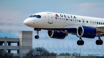 Delta Air Lines aircraft landing against a cloudy blue sky