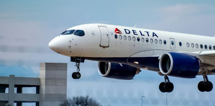 Delta Air Lines aircraft landing against a cloudy blue sky