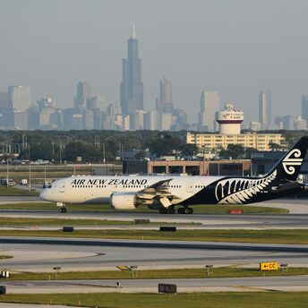 Air New Zealand aircraft on a runway with a city skyline behind it
