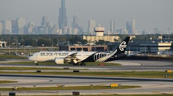 Air New Zealand aircraft on a runway with a city skyline behind it