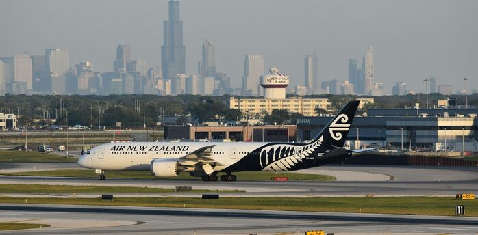 Air New Zealand aircraft on a runway with a city skyline behind it