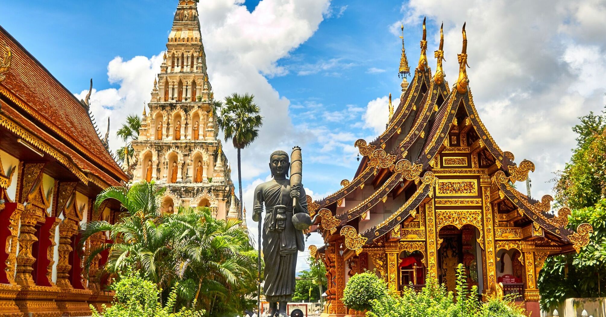 Golden Buddhist temple buildings under a bright blue sky in Thailand