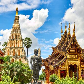 Golden Buddhist temple buildings under a bright blue sky in Thailand