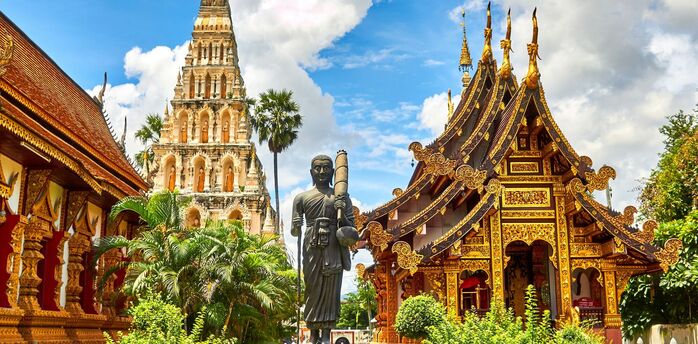 Golden Buddhist temple buildings under a bright blue sky in Thailand